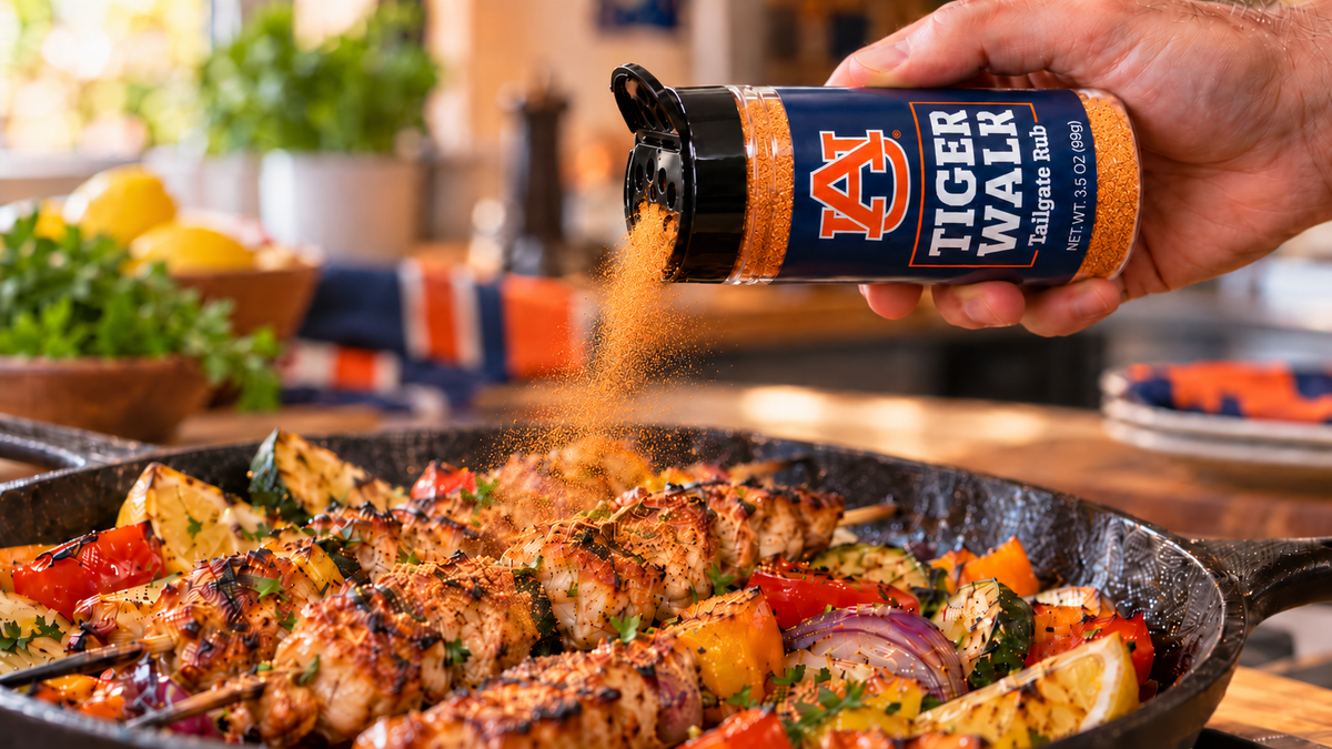 Tiger Walk Tailgate Rub shaken onto chicken skewers in a cast iron pan